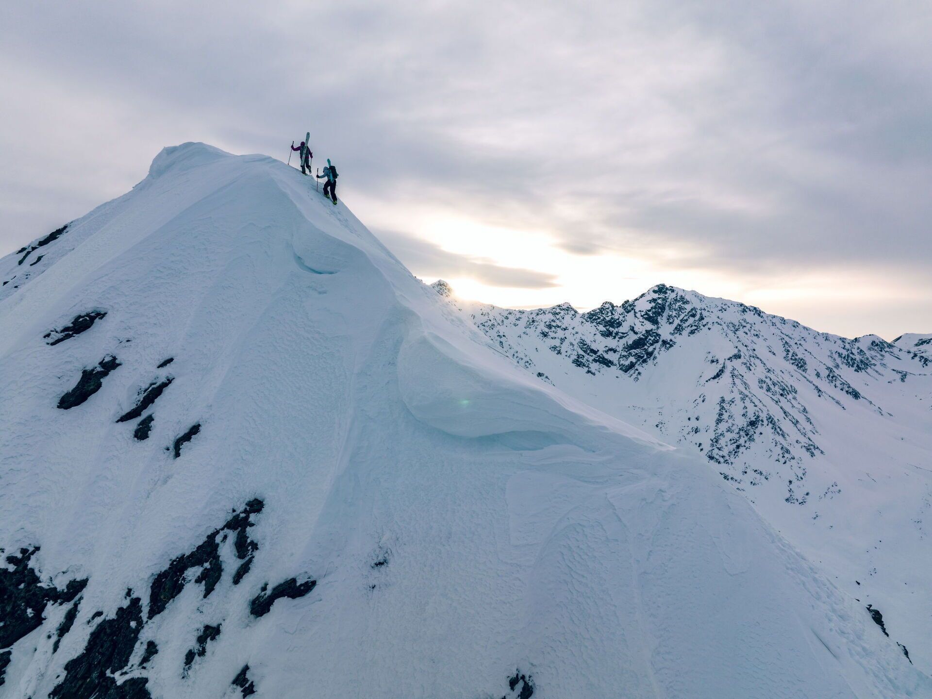 A snow-covered mountain with a glacier and a few skiers at the peak.