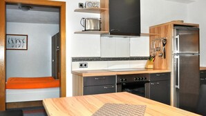 Eine kleine Küche mit einer Holz Arbeitsplatte, einem eingebauten Backofen, einer Mikrowelle und einem Kühlschrank.