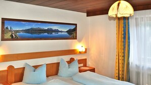Ein Doppelbett mit Holz-Kopfteil, zwei Nachttische, eine Nachttischlampe und ein gerahmtes Landschaftsbild über dem Bett.