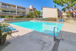 A swimming pool with lounge chairs and a sign indicating pool rules. - Oceanfront Luxury Condo w/ Hot Tub & Pool (Solana Beach)