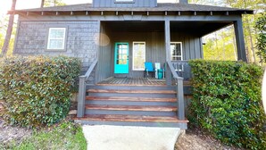 Une maison à deux étages avec un porche, une porte d’entrée et un escalier menant à l’entrée.