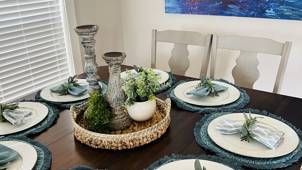 Une table à manger dressée avec des assiettes, des serviettes et un centre de table.