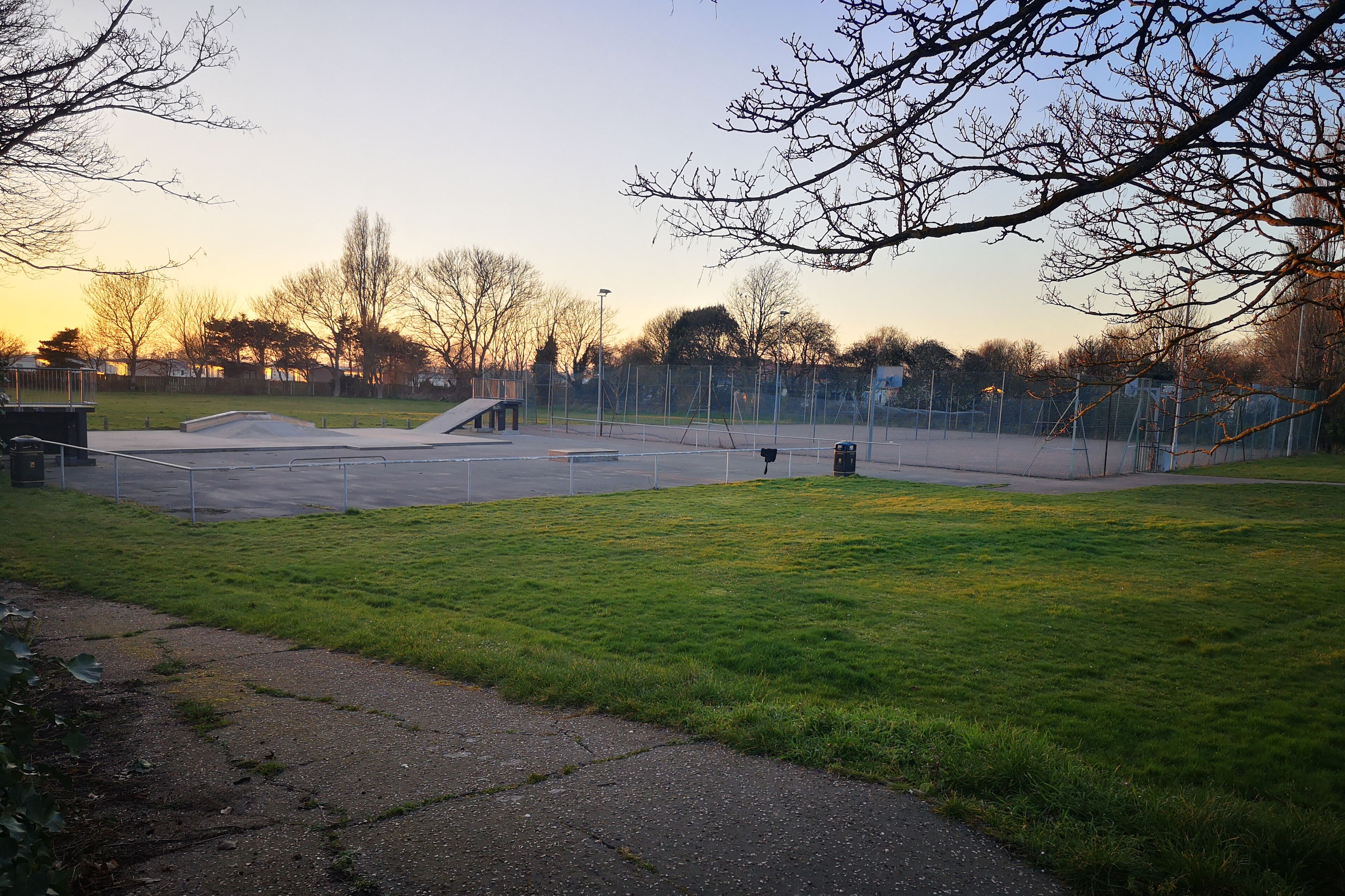 Un parque con un área de juegos, bancos y una zona verde.