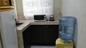Eine kompakte Küche mit Mikrowelle, Toaster und Wasserspender.