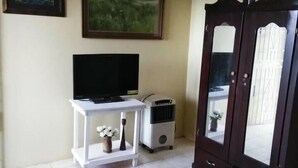 Ein Schlafzimmer mit einem Bett, einem Fernseher auf einem weißen Schrank, einem Heizgerät und einem Kleiderschrank.