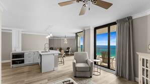 A spacious living area with a kitchen, a balcony with a view of the ocean, and a ceiling fan. - EXQUISITE!  GULF FRONT~5th Floor~ Specials ~ Free Beach Service! Completely Remodeled (Panama City Beach)