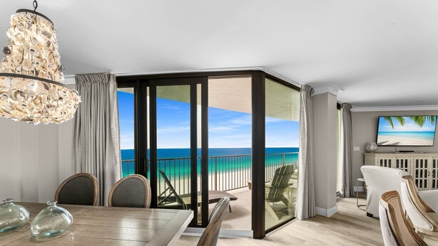 A dining area with a view of the ocean, a television, and a chandelier. - EXQUISITE!  GULF FRONT~5th Floor~ Specials ~ Free Beach Service! Completely Remodeled (Panama City Beach)