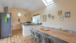 A kitchen with a wooden table and chairs, a refrigerator, and a window with a view of the street. - Gwlgri -  an apartment that sleeps 8 guests  in 4 bedrooms (Holyhead)