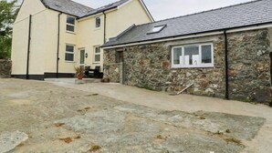 A two-story house with a stone extension, a paved driveway, and a small garden area. - Gwlgri -  an apartment that sleeps 8 guests  in 4 bedrooms (Holyhead)