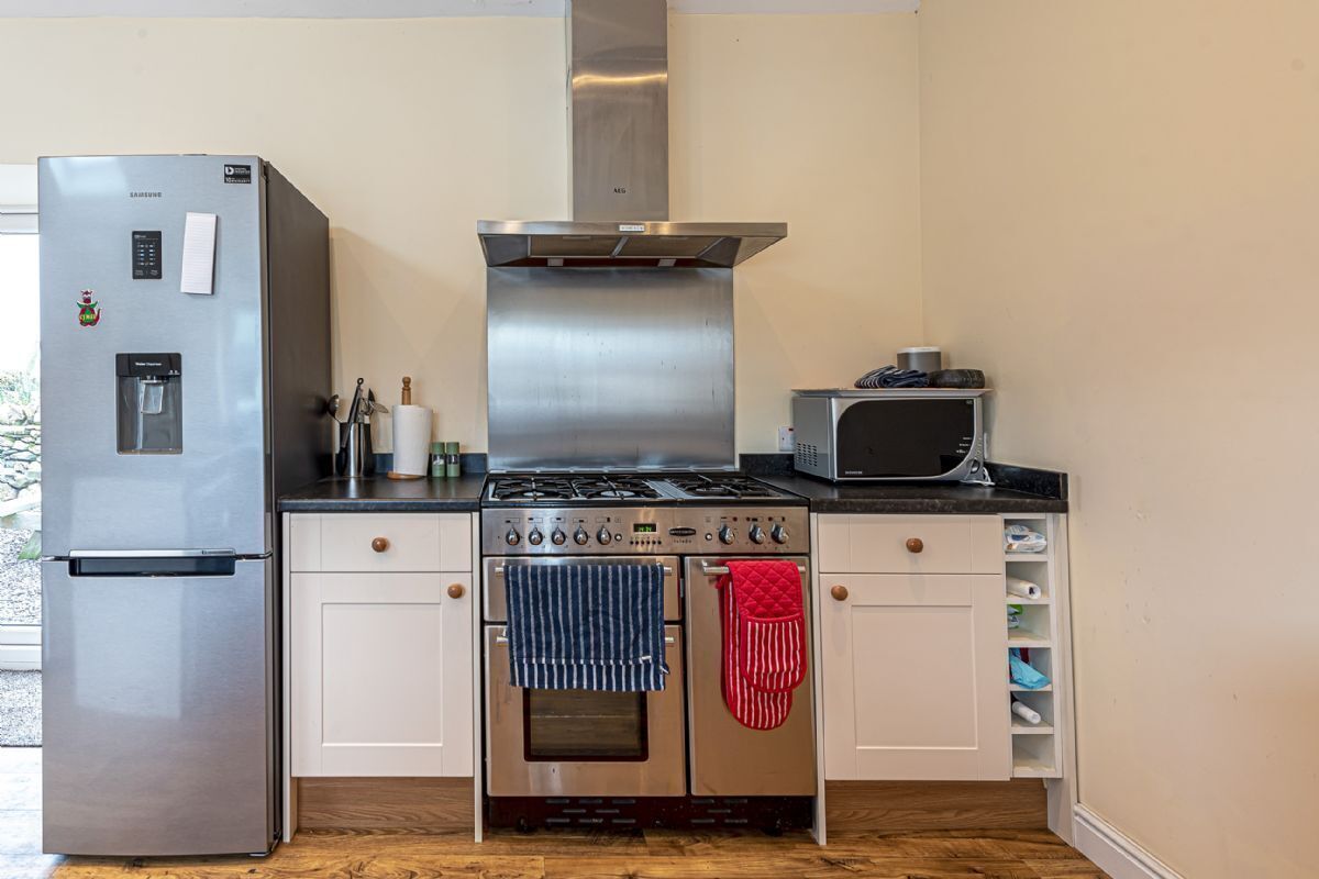 Una cocina compacta con refrigerador de acero inoxidable, horno empotrado, microondas y cocina a gas.