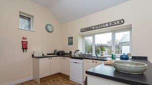 A kitchen with white cabinets, a dishwasher, a sink, and a window with a view of the outside. - Gwlgri -  an apartment that sleeps 8 guests  in 4 bedrooms (Holyhead)