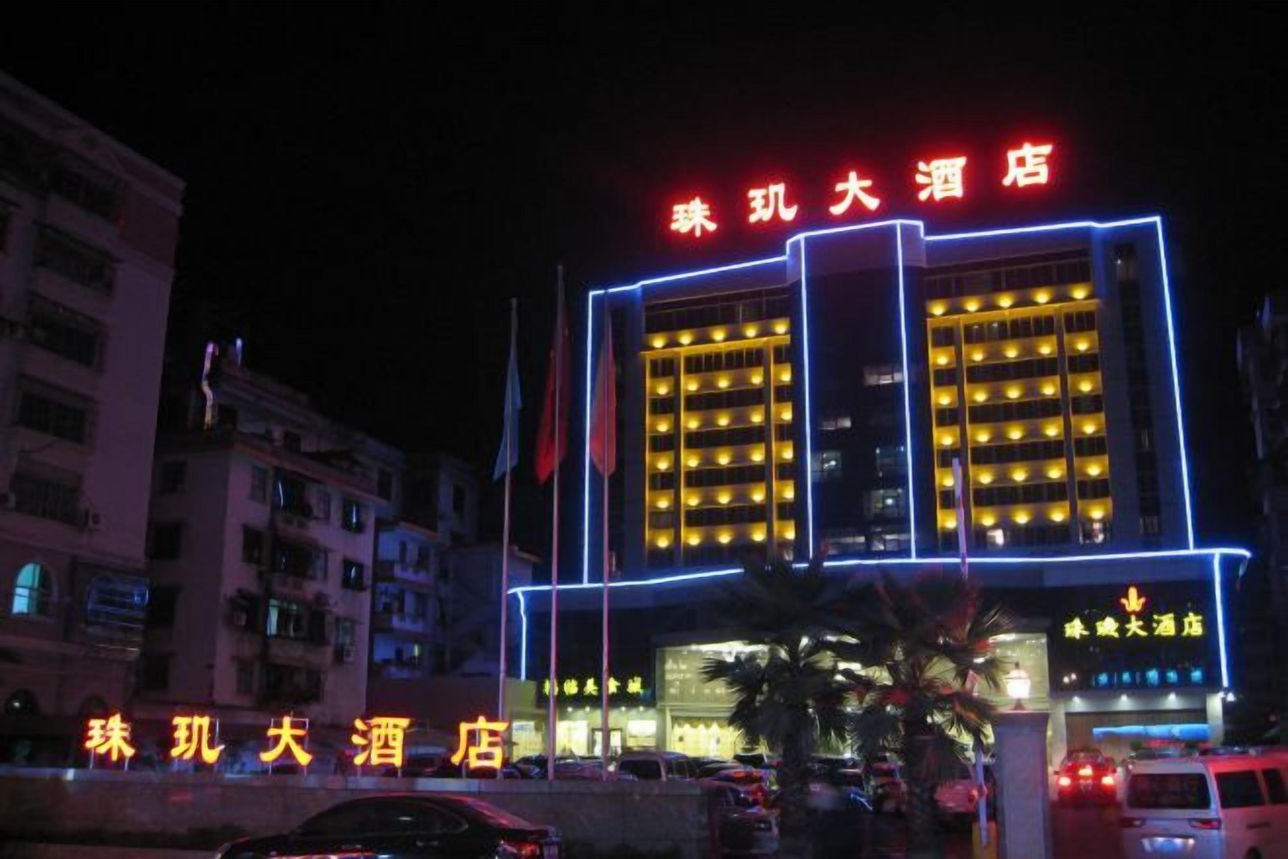A hotel with a prominent red sign, multiple floors, and a well-lit facade.