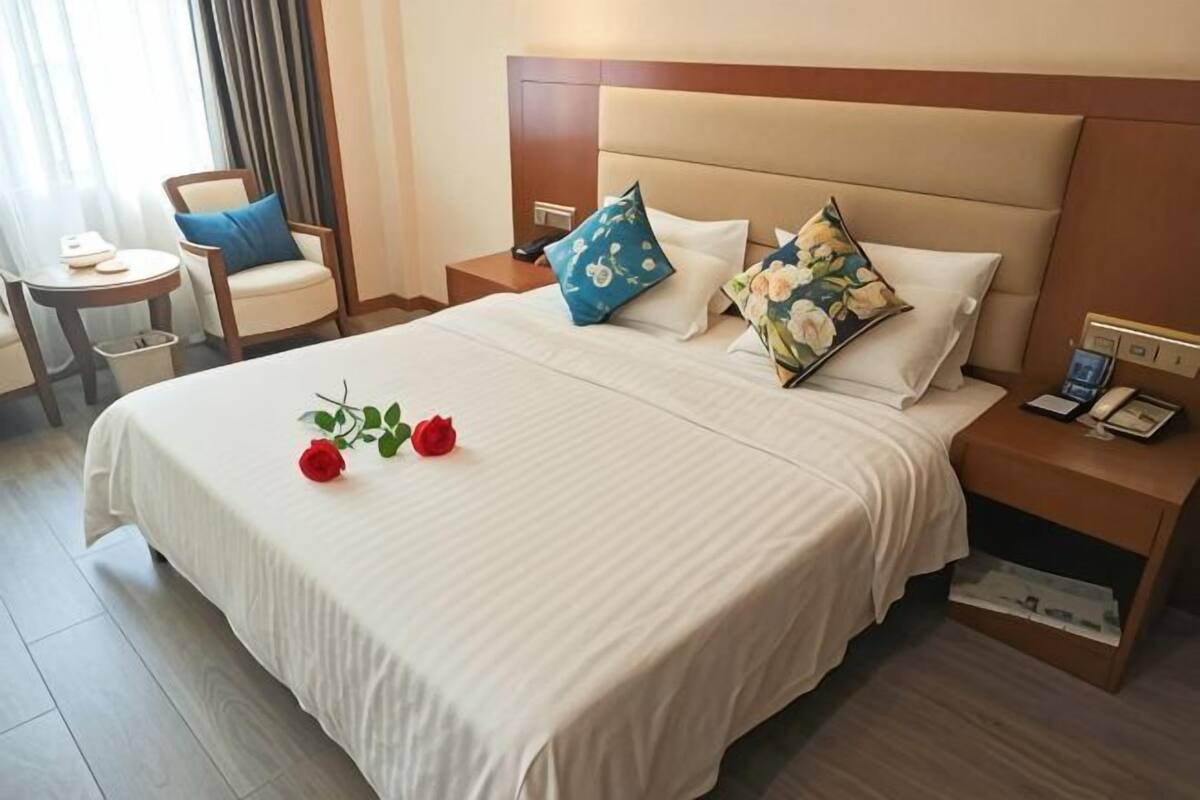 Una habitación de hotel con una cama grande, dos mesitas de noche, una silla y una pequeña mesa.
