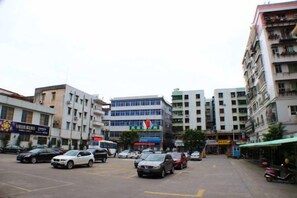 Un edificio de varios pisos con una entrada central, rodeado de coches aparcados y otros inmuebles.