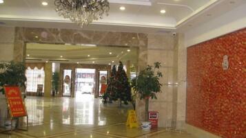 A hotel lobby with a chandelier, marble flooring, and Christmas decorations.