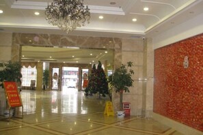Een hotel lobby met een kroonluchter, marmeren vloeren en kerstversiering.