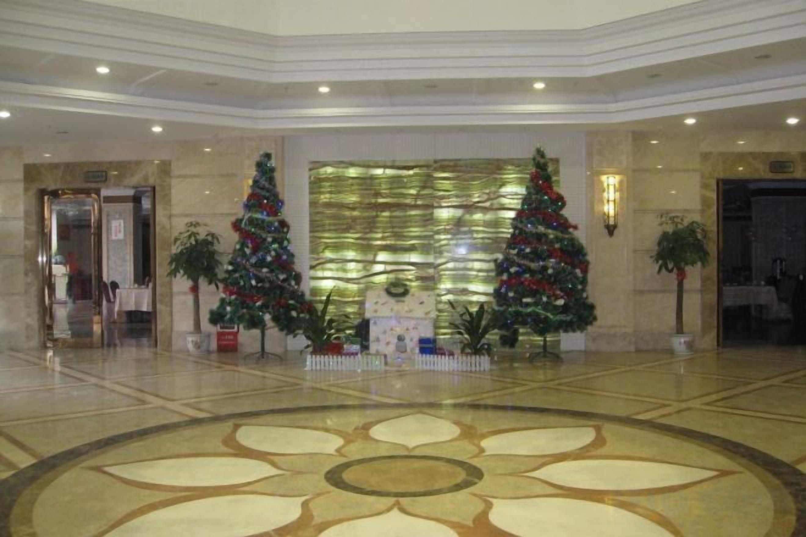 Eine Empfangshalle mit zwei Weihnachtsbäumen, einer großen Wanddekoration und einem gemusterten Boden.