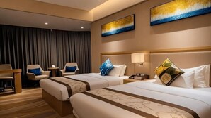 Una habitación de hotel con dos camas, un escritorio, sillas y obras de arte en las paredes.