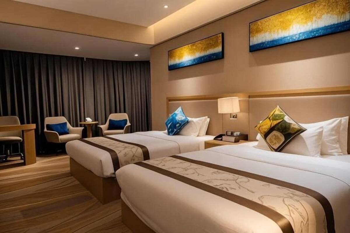 Una habitación de hotel con dos camas, un escritorio, sillas y obras de arte en las paredes.