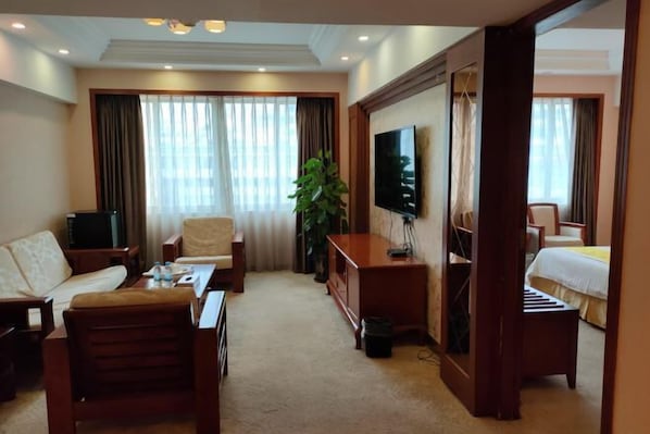 Une chambre d’hôtel avec un canapé, un fauteuil, une télévision et un lit.
