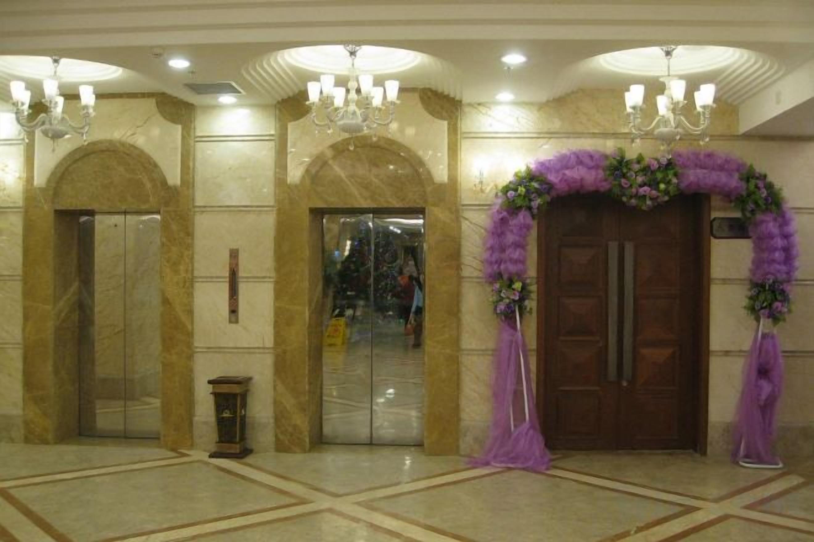 Eine Lobby mit Marmorboden, Doppeltüren und einem Chandelier.