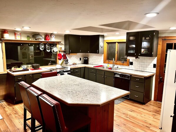 A modern kitchen with dark cabinets, a granite countertop, and a built-in island with bar stools.