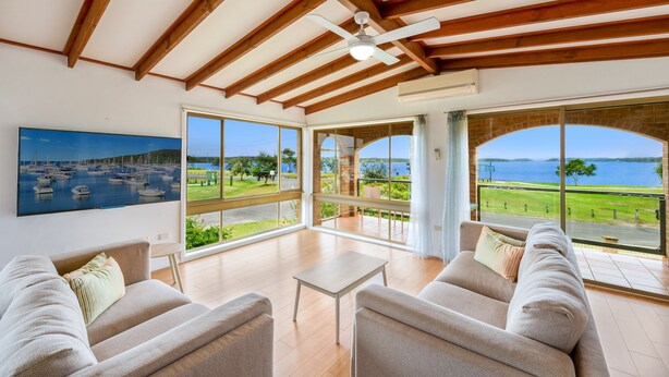 Ein geräumiges Wohnzimmer mit großem Fenster und Blick auf einen Yachthafen und das Meer.