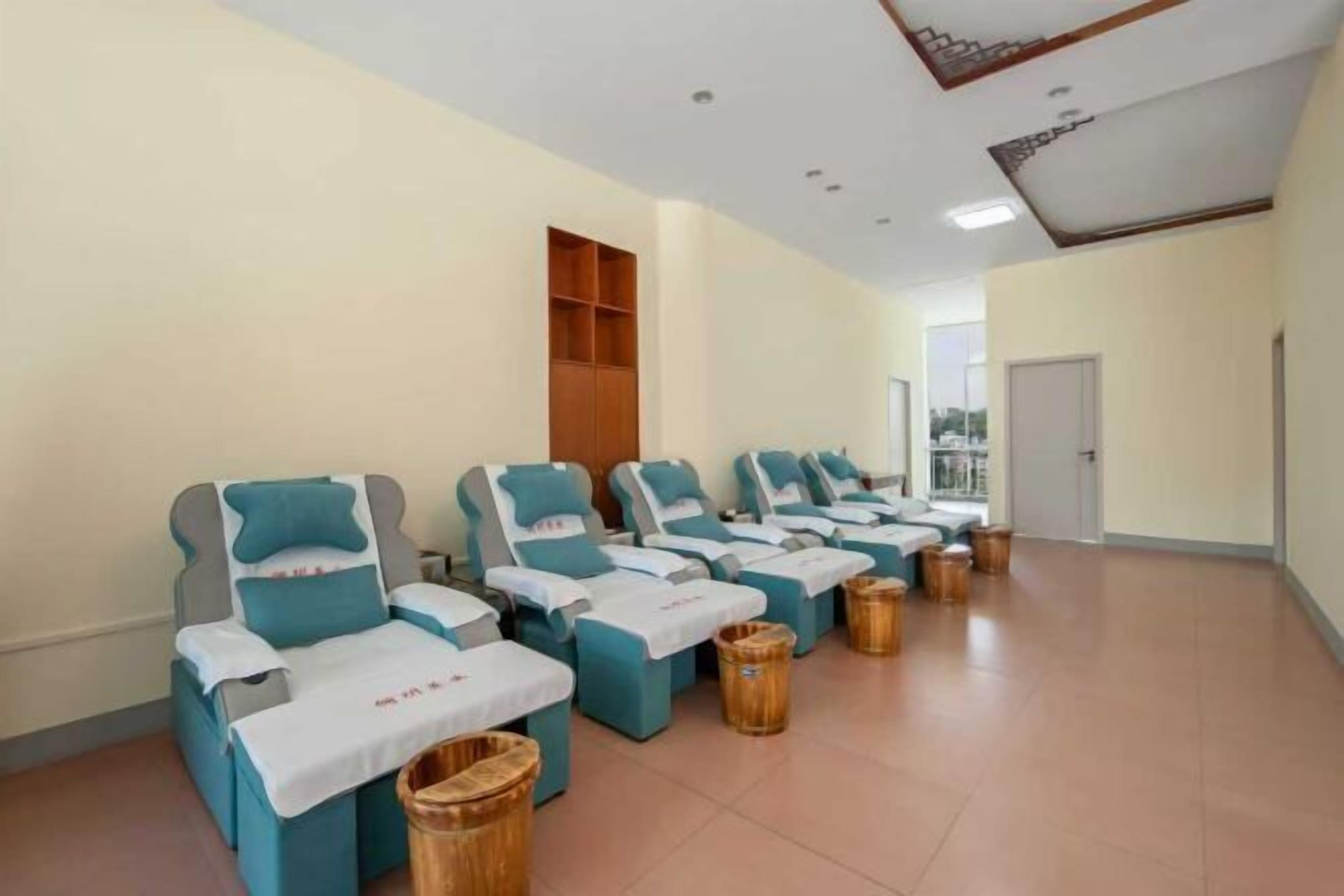 A room with multiple massage chairs arranged in a row, each with a small table and a trash bin.