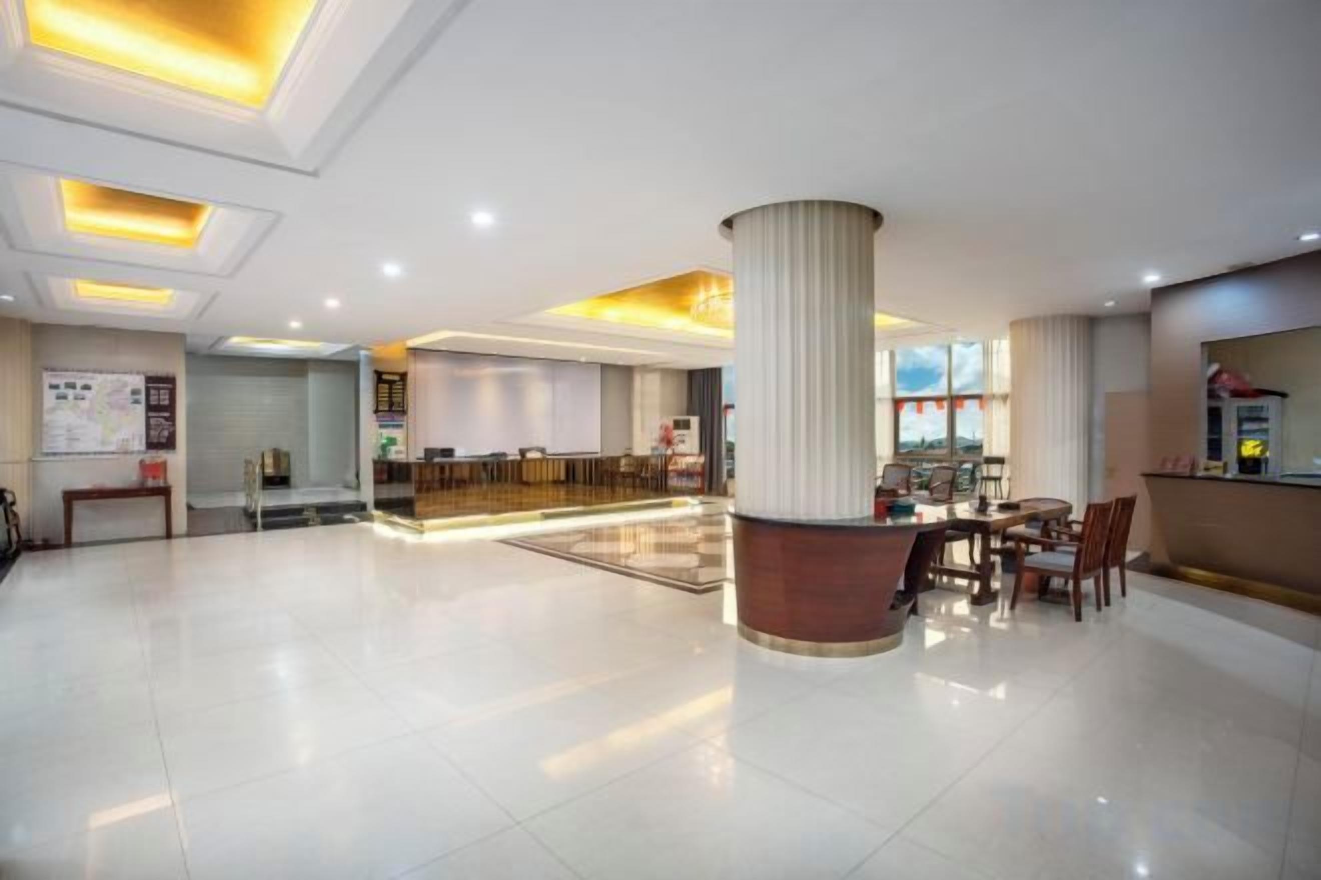 A hotel lobby with a reception desk, seating area, and a large pillar.