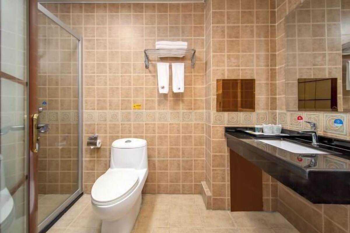 A bathroom with a toilet, a shower, and a sink.