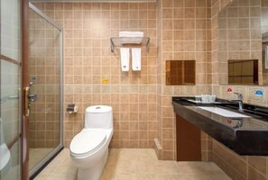 A bathroom with a toilet, a shower, and a sink.