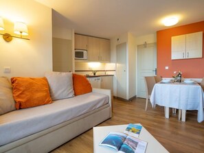 Un apartamento moderno con sofá, mesa de comedor y zona de cocina.