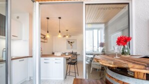 Una cocina moderna con armarios blancos, encimera de madera e iluminación colgante.