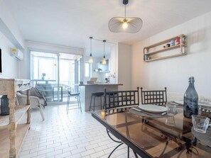 A modern kitchen with a glass dining table, bar stools, and pendant lighting. - Hacienda 3 by Interhome (Canet-Plage)