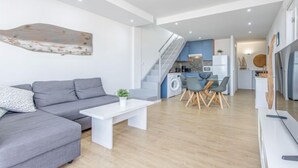 A modern living room with a grey sofa, a white coffee table, and a dining area with chairs and a table. - Port Canigó by Interhome (Roses)