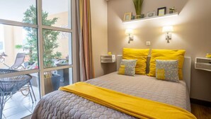 A hotel room with a large bed, a balcony with a chair, and a view of the outside. - L'Esquinade P3 314 by Interhome (Agay Village Cap Esterel)