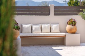 A modern outdoor seating area with a bench, cushions, and a potted plant.
