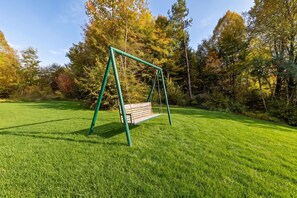 A green swing set in a grassy park with trees in the background. - Chalet With Private Whirlpool And Sauna, Zavrh, Croatia (Zavrh)