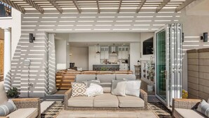 Uma sala de estar moderna com um conjunto de sofás, uma mesa de centro e uma cozinha ao fundo.