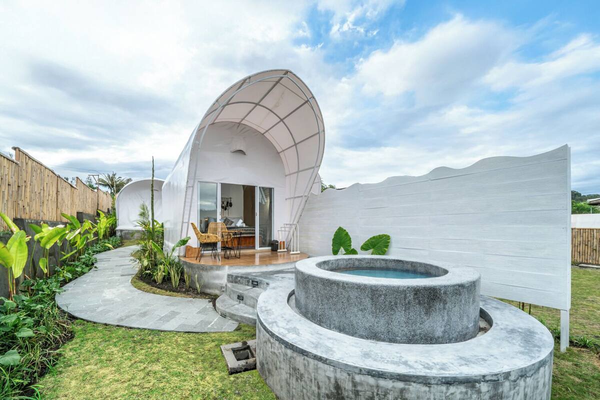 Eine moderne, kuppelartige Struktur mit Terrasse und einem Wasserspiel aus Stein.