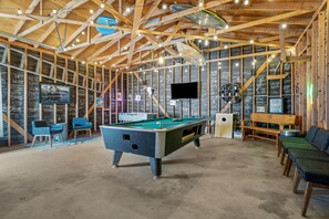 Relax and socialize in this spacious indoor recreational area featuring a pool table, seating arrangements, and a flat-screen TV.