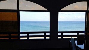 Una habitación con vista al océano a través de ventanales de arco.