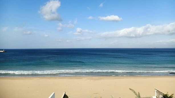 Una playa con cielo despejado y mar tranquilo.