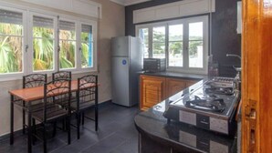 Een keuken met een eettafel, stoelen, een koelkast en een fornuis.
