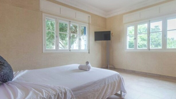 Een hotelkamer met een groot bed, twee ramen, een flatscreen televisie en uitzicht op groen.