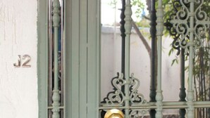 Une porte métallique verte, dotée d’un cadenas en laiton et d’un trou de serrure, et une porte blanche sur laquelle on peut voir le numéro « J2 ».