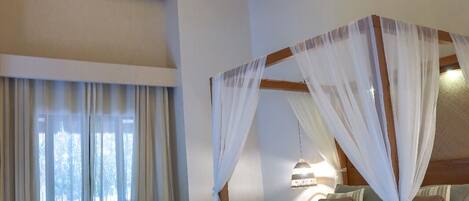 A bedroom with a four-poster bed, a sofa, and a large window with curtains.