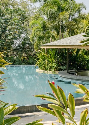 A swimming pool surrounded by lush greenery and a covered pavilion.