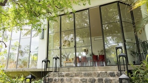 Un edificio moderno con amplios ventanales de vidrio, escalones de piedra y mobiliario exterior.