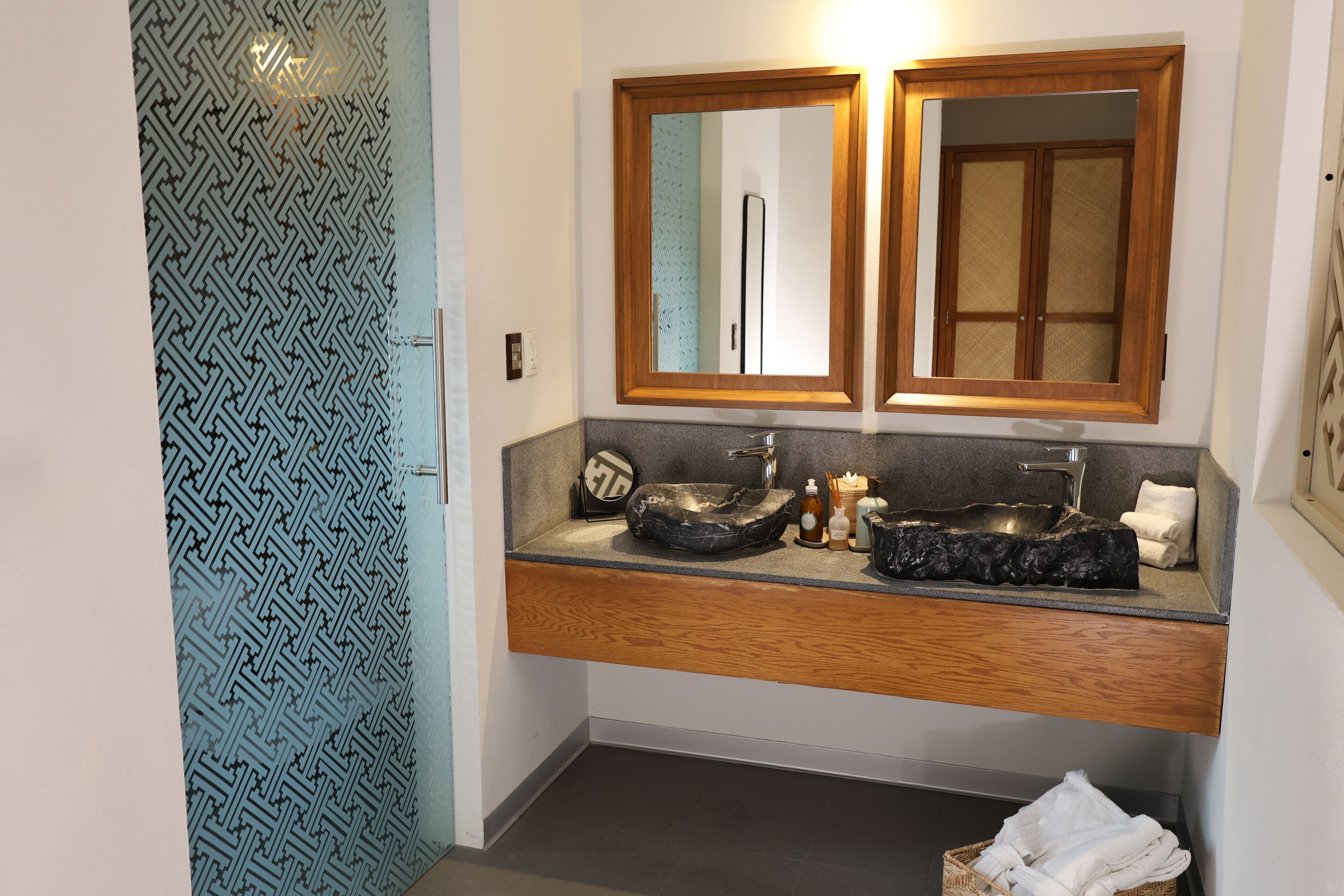 Ein Badezimmer mit einem Doppelwaschbecken, einem Holzwaschtisch und einer Wand mit Muster.